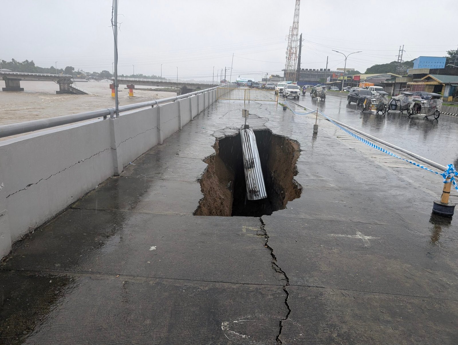 Large sinkhole and widening cracks along rain-soaked Aquino Boulevard beside the Tarlac River